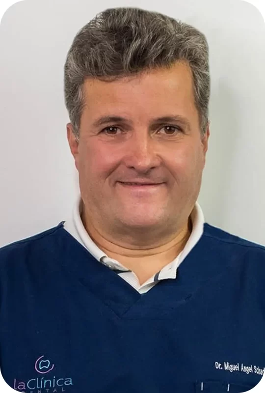 Dr. Miguel Angel S., specialist in endodontics, wearing a dental coat, smiling against a neutral background, representing La Clínica Dental.