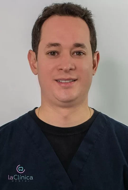 Dr. Freddy José M., specialist in maxillofacial surgery at La Clínica Dental, smiling in professional attire against a neutral background.