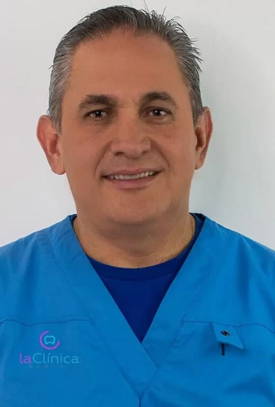Dentist in blue scrubs smiling, representing La Clínica Dental, specializing in quality dental care and advanced technology.