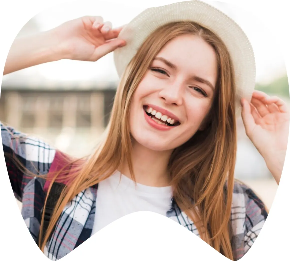 Joven sonriente con sombrero, mostrando dientes saludables, simbolizando turismo dental y bienestar en México.