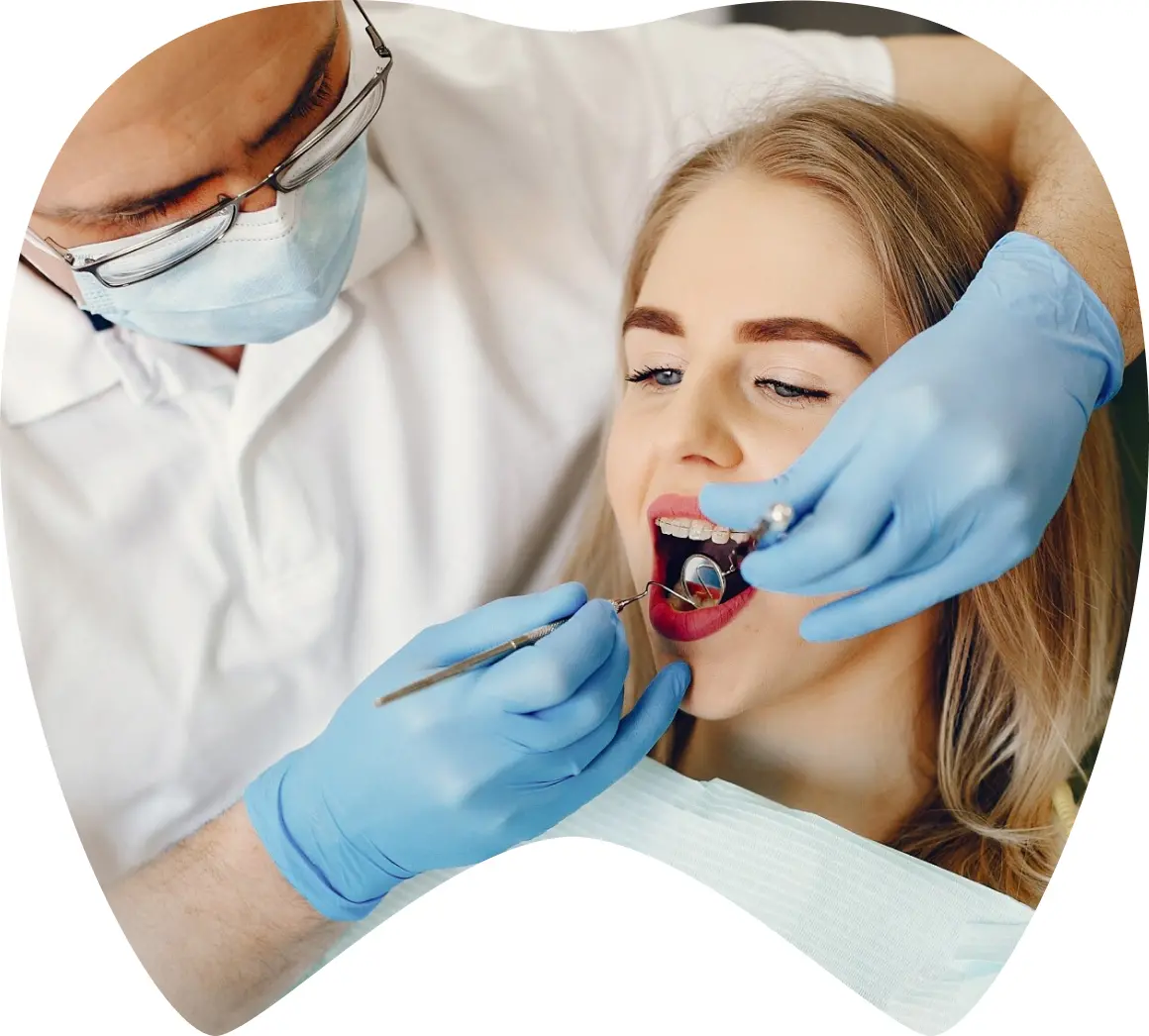 Dentist examining patient with braces, highlighting dental care and treatment at La Clínica Dental Roma in Mexico.