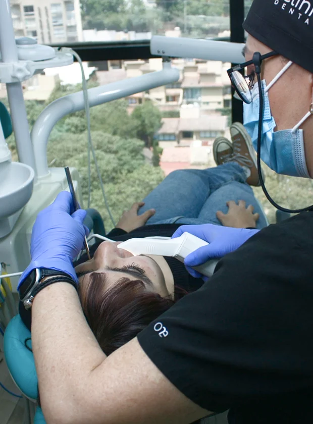 Dentist providing dental treatment to a patient in a modern clinic setting, showcasing advanced dental technology and professional care at La Clínica Dental Roma.