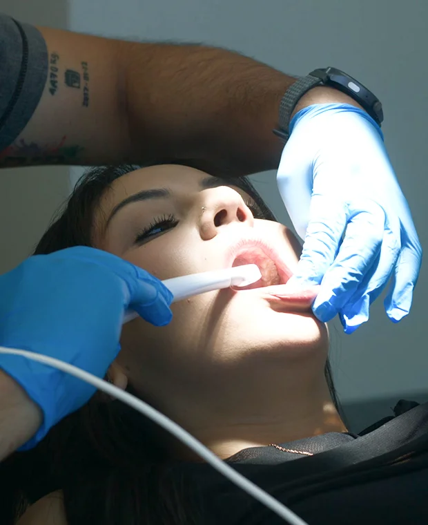 Dentist performing oral examination on a patient using dental tools, highlighting advanced dental care at La Clínica Dental Roma.