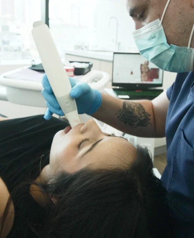 Dentist using intraoral scanner on a patient in a modern dental clinic, emphasizing advanced technology for dental treatments.