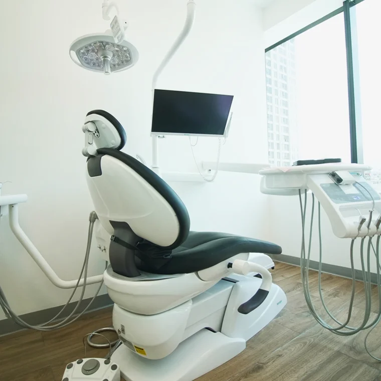 Dental treatment room featuring a modern dental chair, overhead light, and monitor, emphasizing La Clínica Dental Roma's commitment to advanced technology and patient care.