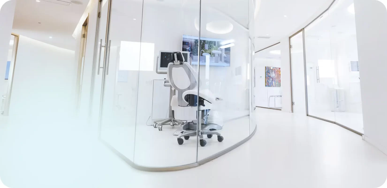 Consultorio dental moderno con silla de tratamiento y pantalla, diseño minimalista y luminoso, reflejando servicios de alta estética en La Clínica Dental.