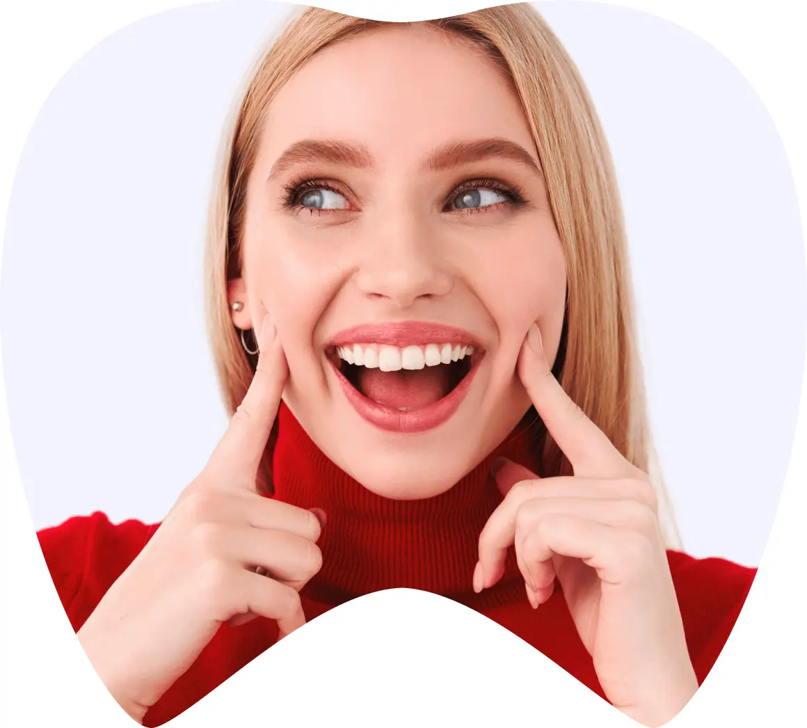 Mujer sonriente con dientes brillantes, señalando su sonrisa, simbolizando la satisfacción de tratamientos dentales en La Clínica Dental Roma.